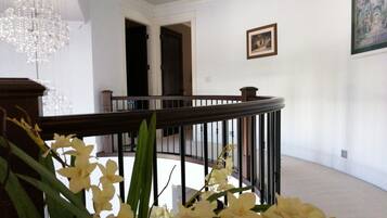A grand staircase with a wooden handrail and black balusters, leading to an upper floor.