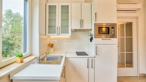 A modern kitchen with white cabinets, a built-in microwave, and a window providing a view of greenery outside. - Apartment in Rovinj with Balcony, Air condition, WIFI, Dishwasher (4286-3) (Rovinj)