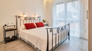 A neatly arranged bedroom with a metal bed frame, white bedding, and a small bedside table with a lamp. - Apartment in Rovinj with Balcony, Air condition, WIFI, Dishwasher (4286-3) (Rovinj)