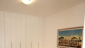 A bedroom with a bed, a nightstand, a wall-mounted painting, and a wardrobe.