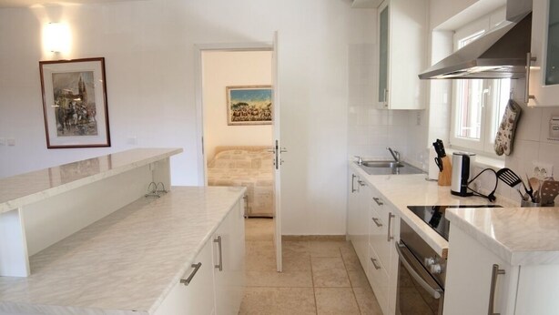 A modern kitchen with white cabinets, a marble countertop, and a built-in oven.