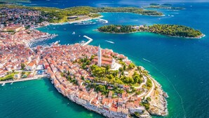 An aerial view of a coastal town with a historic center, marina, and surrounding islands.