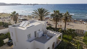 Ein modernes, weißes Gebäude mit Dachterrasse und Blick auf einen Strand.