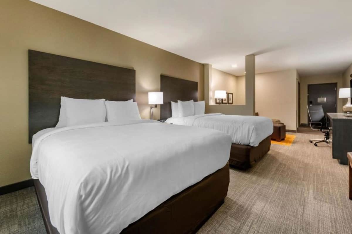A hotel room with two beds, a desk, and a chair.