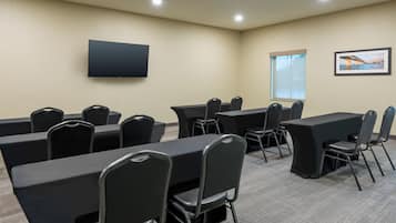 A conference room with tables and chairs, a flat-screen TV, a window with a view, and a framed picture on the wall.