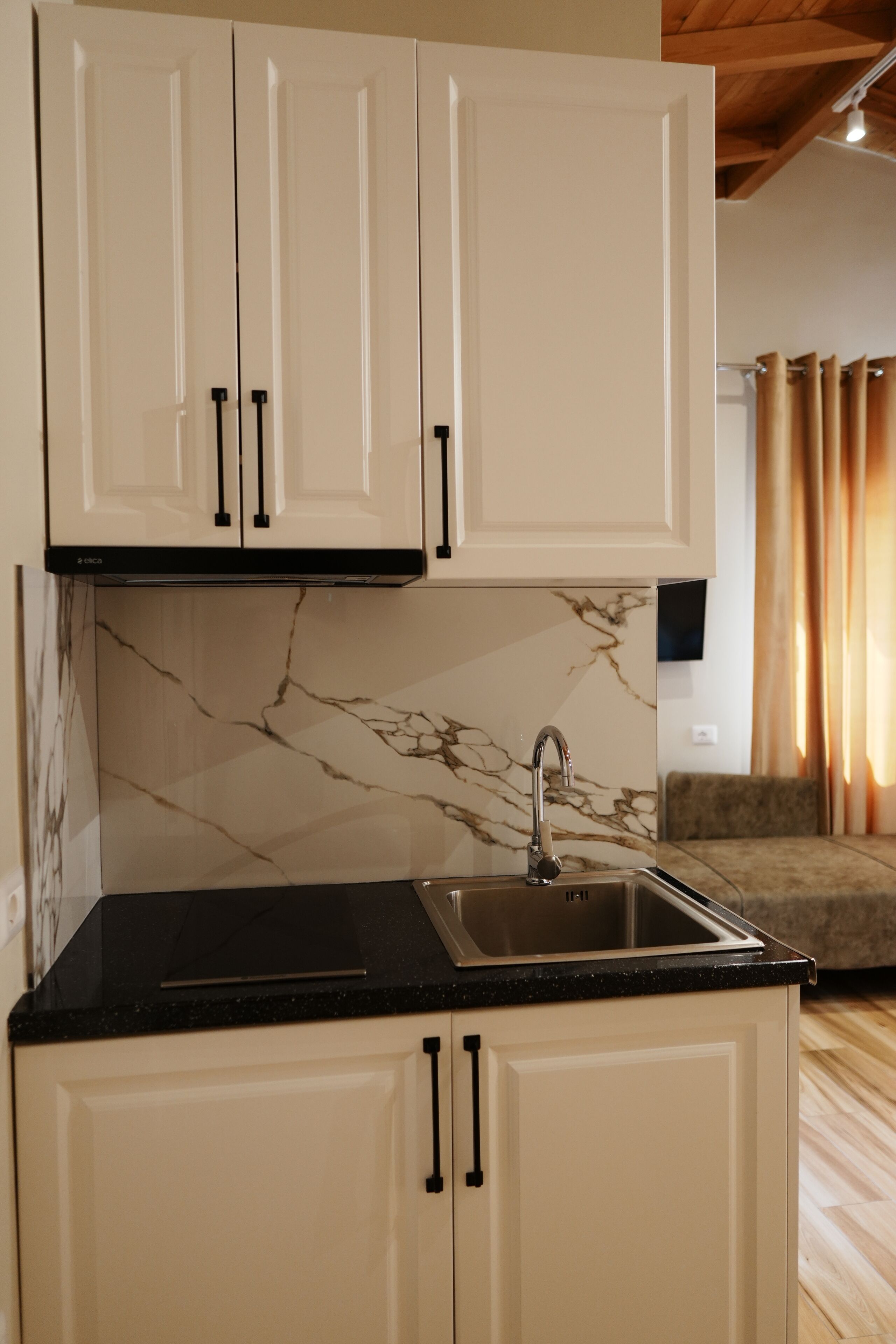 A kitchen with white cabinets, a black countertop, and a marble backsplash.