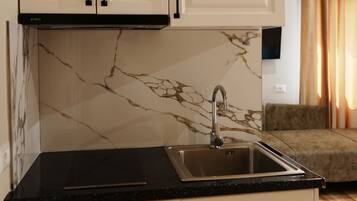A kitchen with white cabinets, a black countertop, and a marble backsplash.