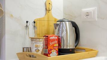 Una bandeja con una cafetera, una caja de café Lavazza Surname, un tarro de cristal y una botella de agua sobre una encimera de cocina.