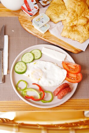 A plate with an egg, cucumber slices, tomato, and bell pepper on a table.