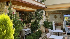 A multi-level outdoor seating area with stone walls, wooden beams, and potted plants.