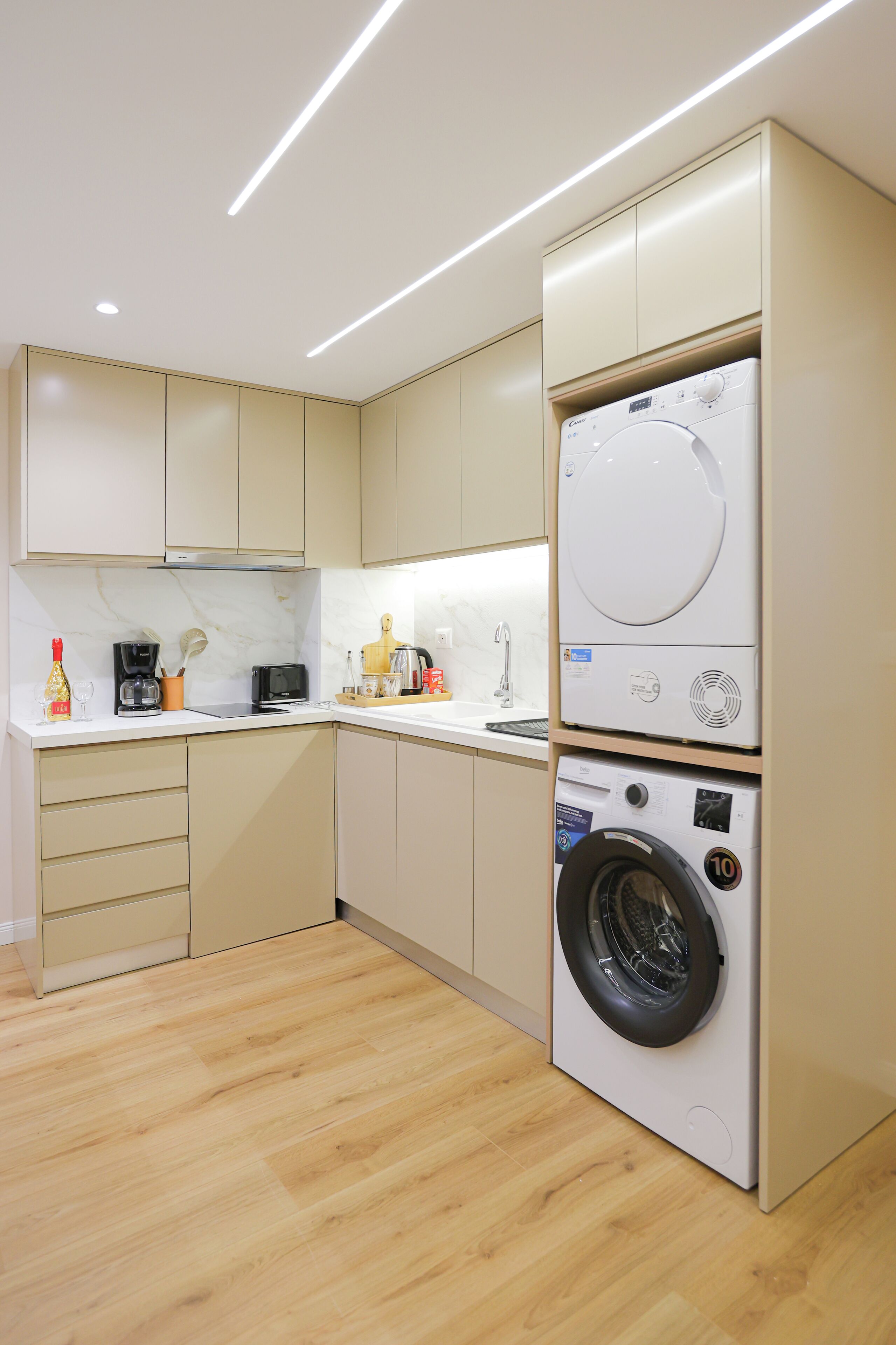 A compact kitchen with a built-in washer and dryer, wooden flooring, and modern cabinetry.