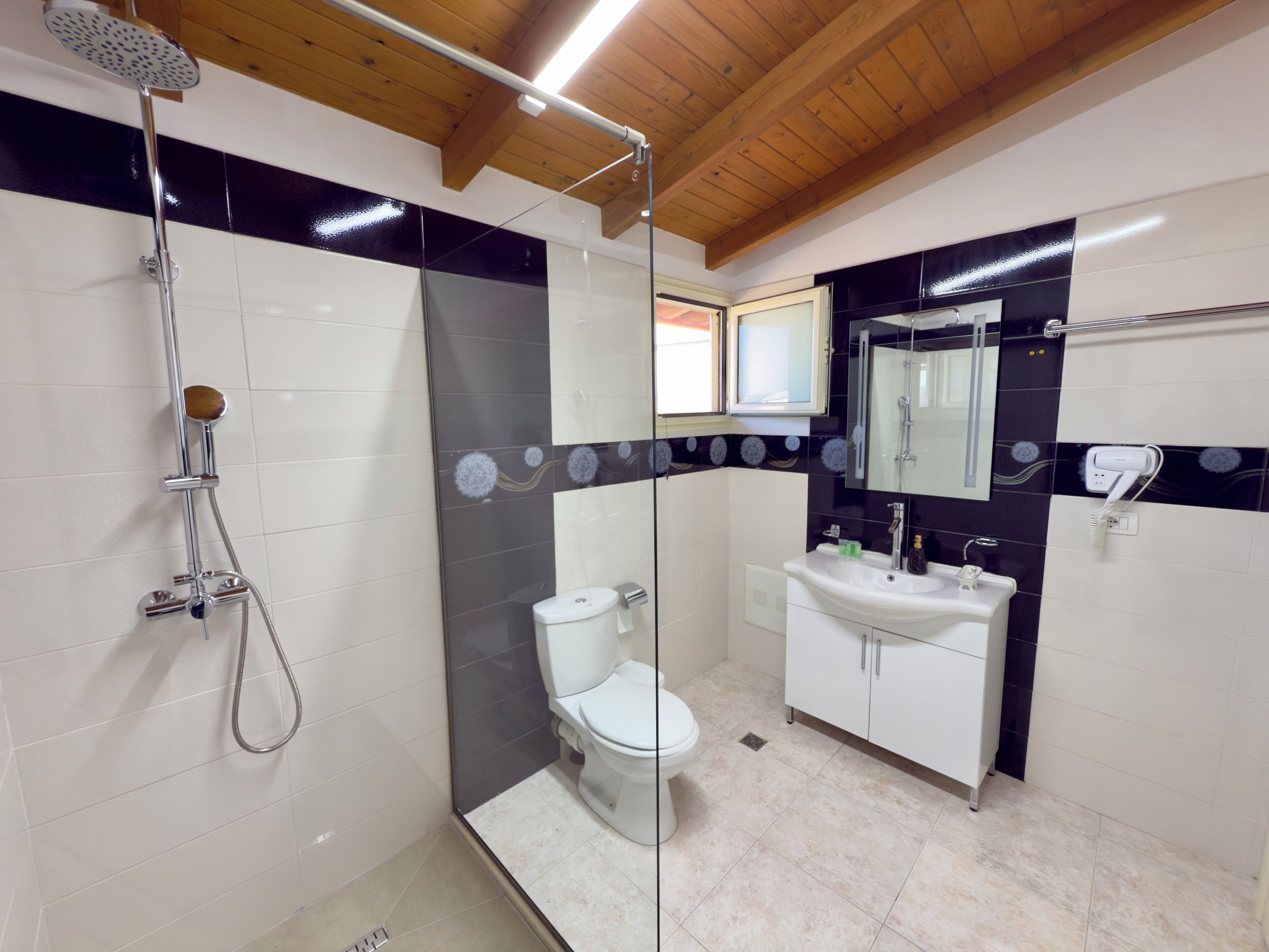 A bathroom with a shower, toilet, sink, and mirror.