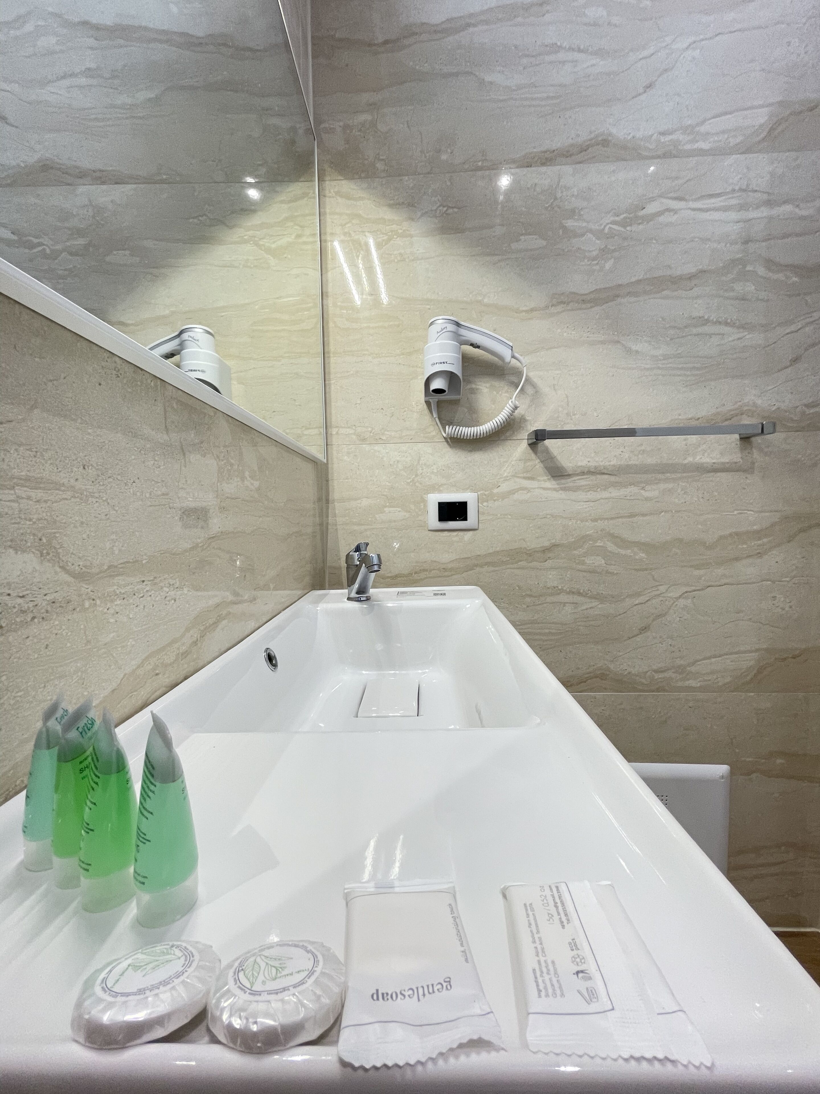 Une salle de bain moderne avec un grand lavabo, un sèche-cheveux et un porte-serviettes.