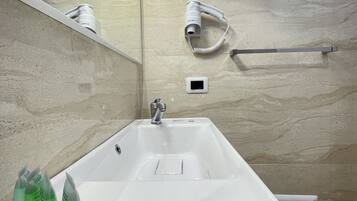 A modern bathroom with a large sink, a handheld hair dryer, and a towel rack.