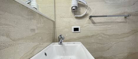 A modern bathroom with a large sink, a handheld hair dryer, and a towel rack.