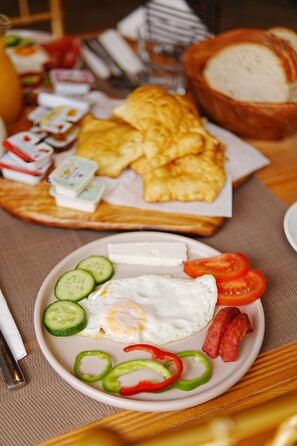 A breakfast plate with eggs, tomatoes, cucumbers, and peppers.