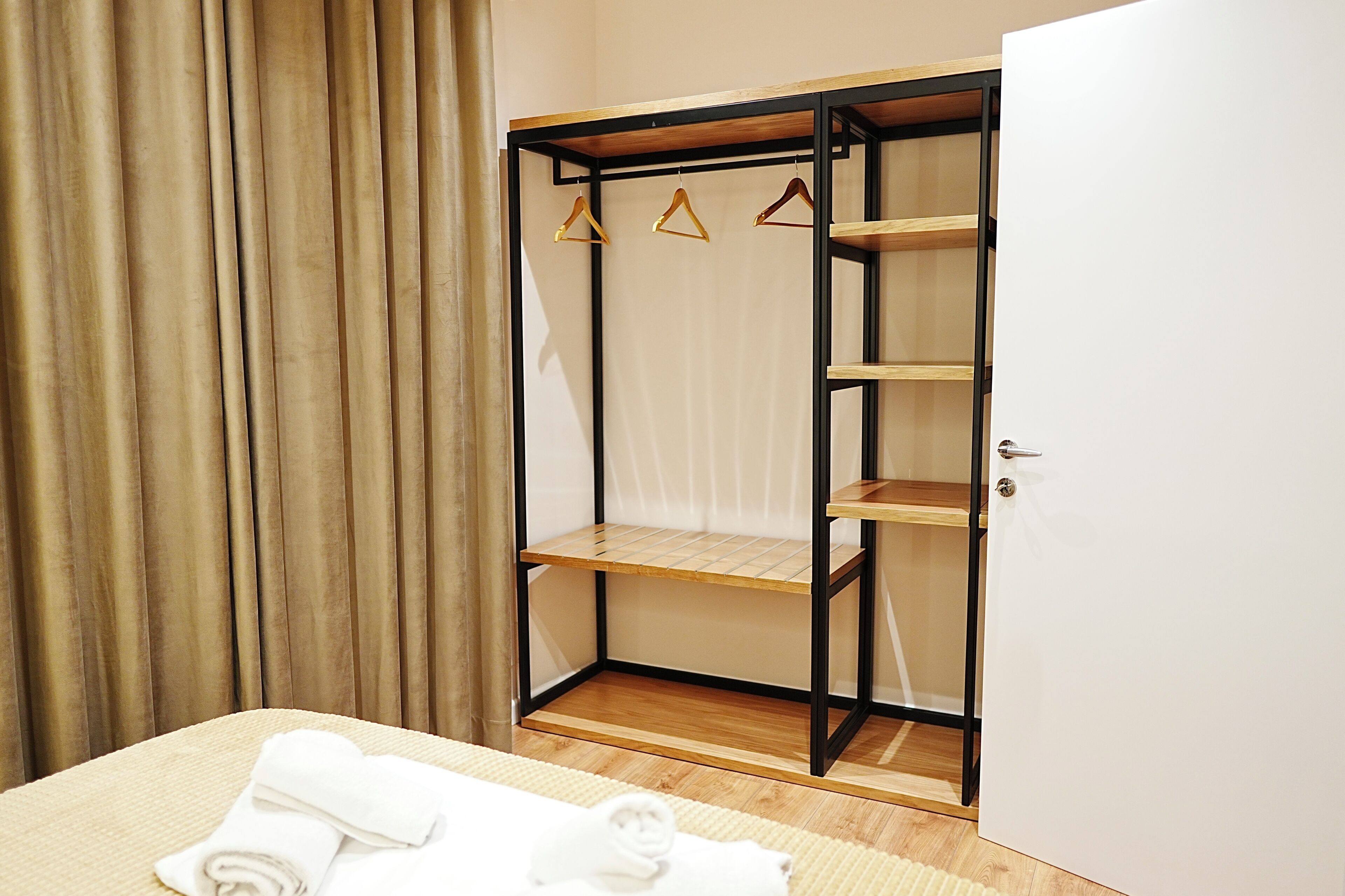 A room with a bed, a wooden wardrobe with shelves, and a door.
