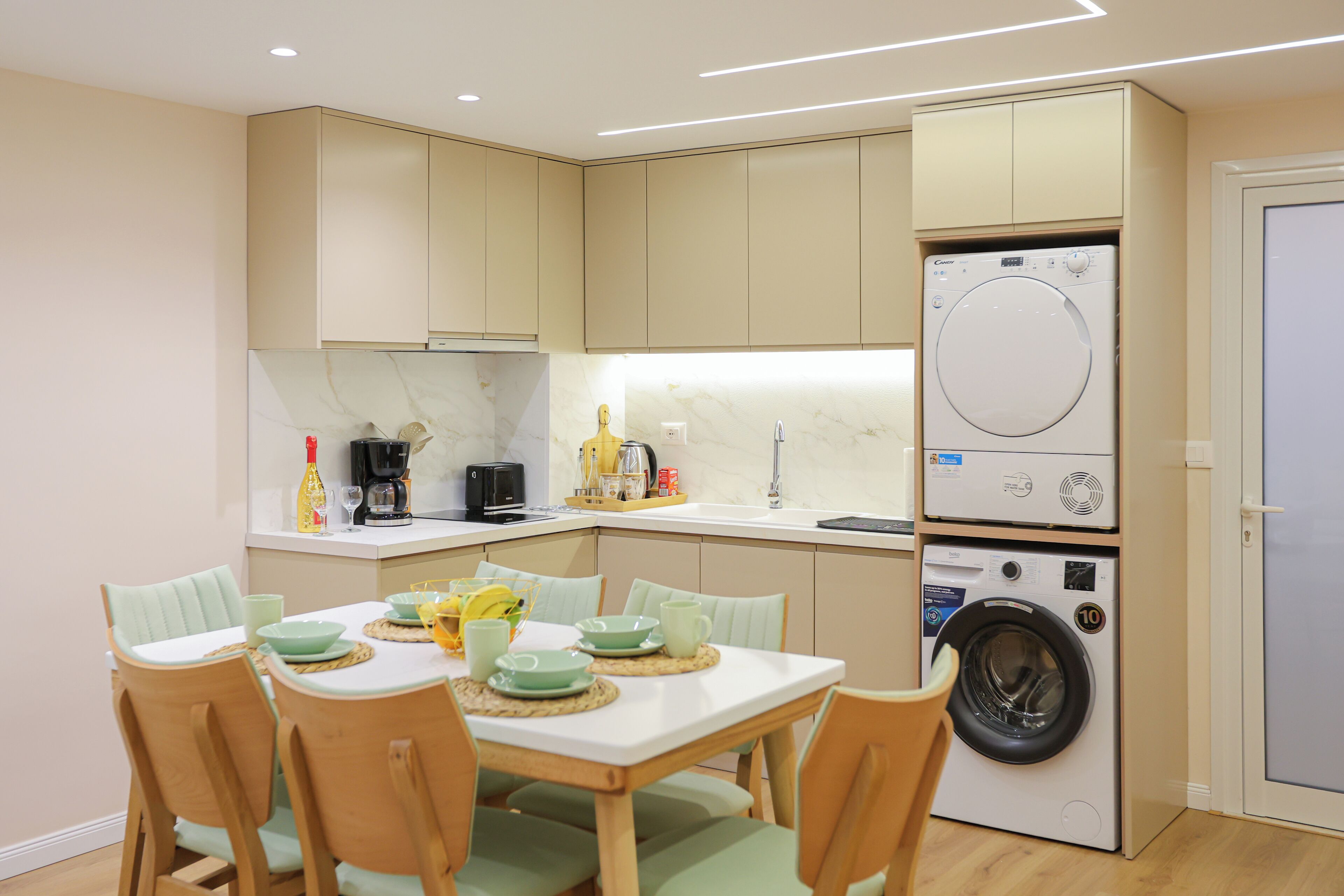 A compact kitchen with a built-in washer and dryer, a dining table with chairs, and a breakfast bar.