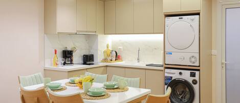 A compact kitchen with a built-in washer and dryer, a dining table with chairs, and a breakfast bar.