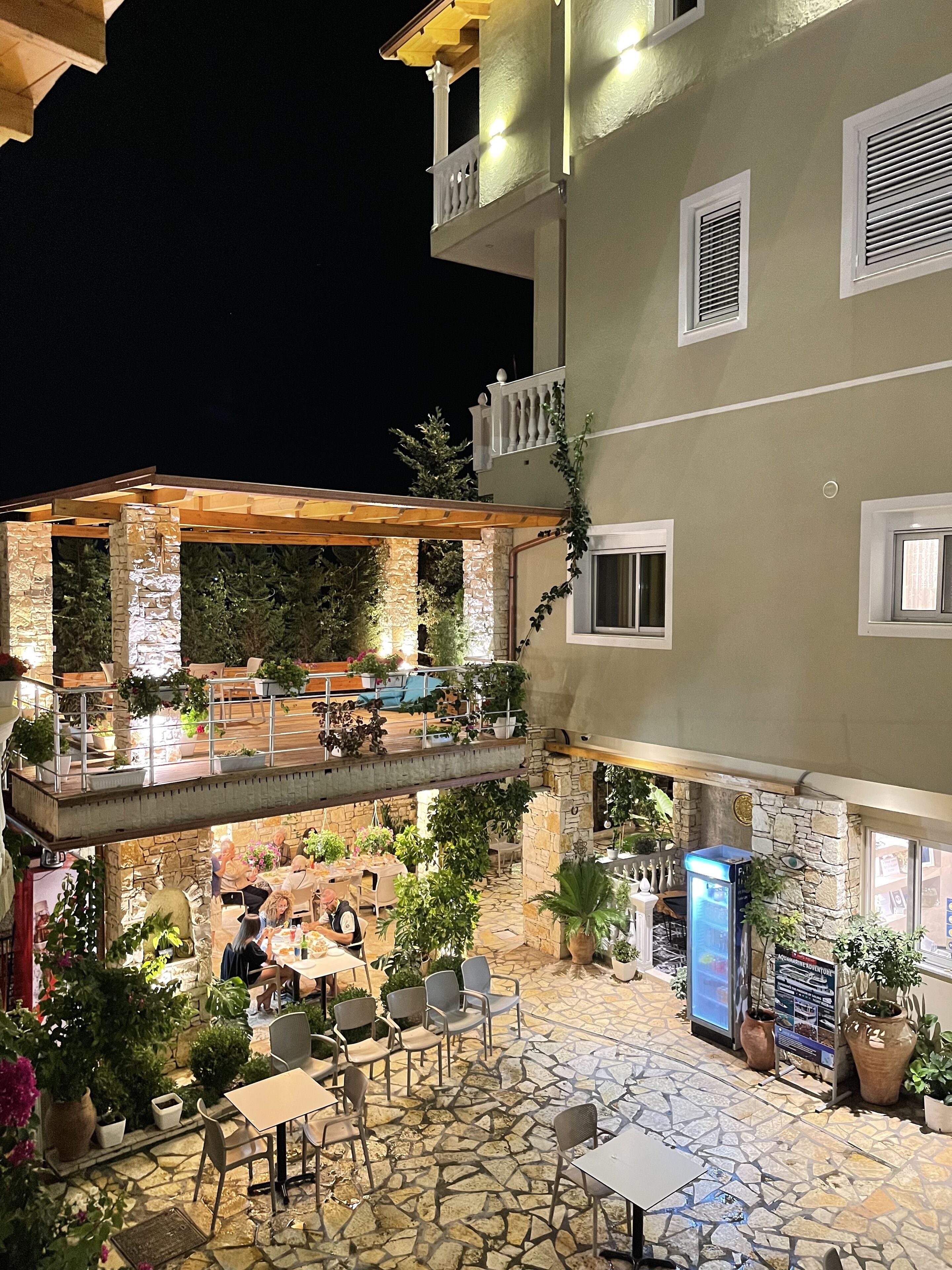 A multi-level outdoor patio with stone flooring, seating areas, and potted plants.