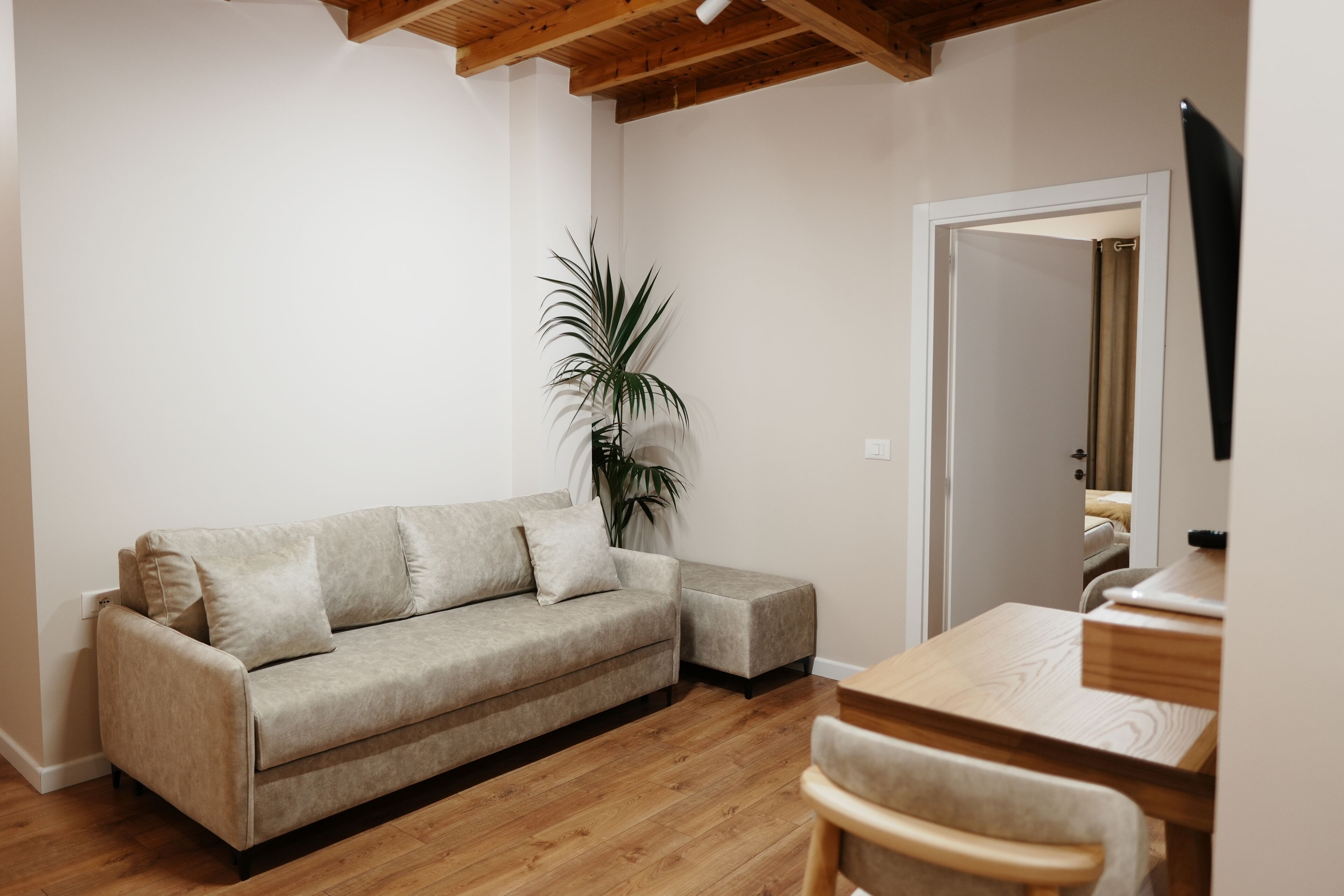 A living room with a sofa, a small table, a chair, and a potted plant.