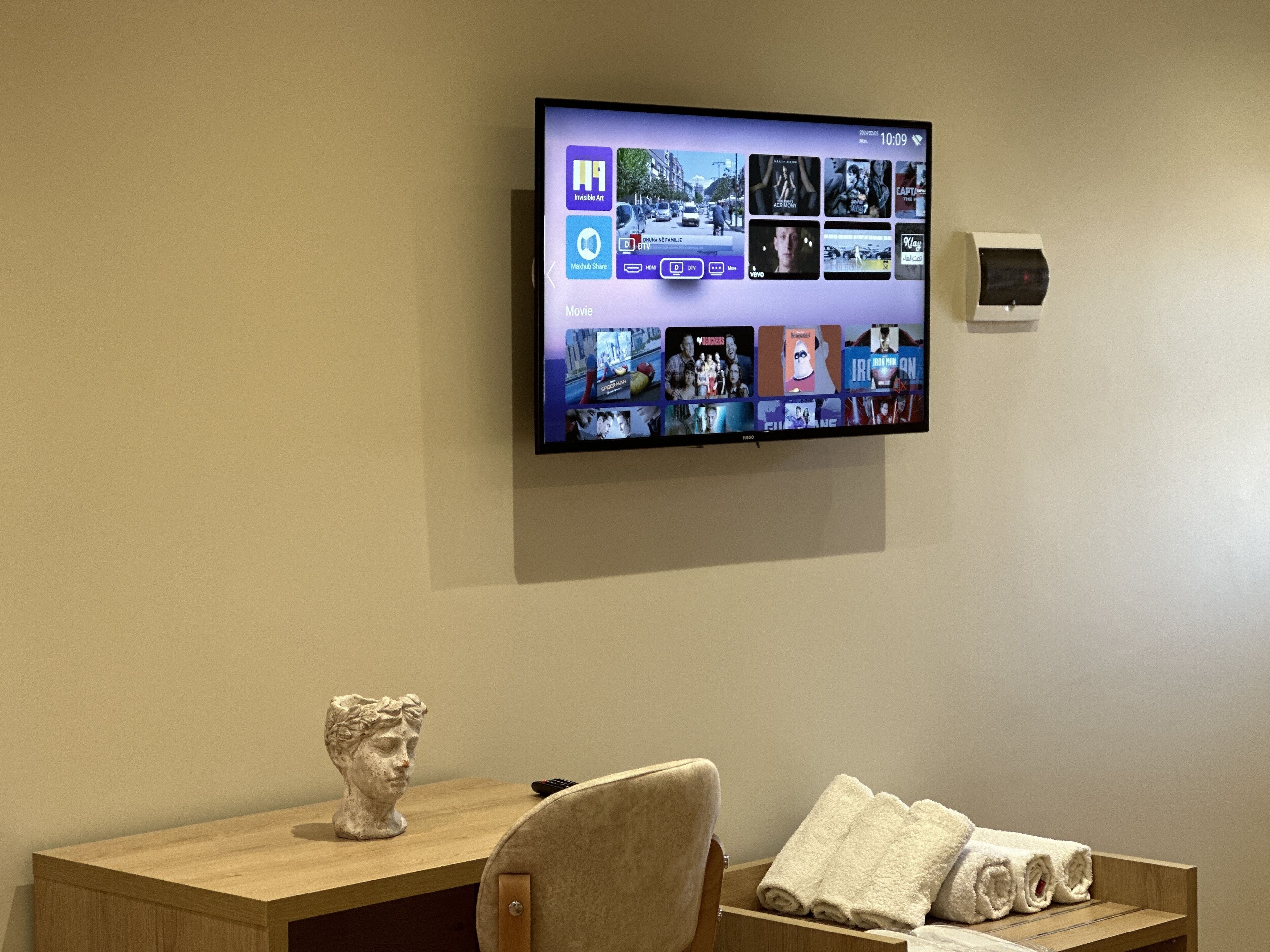 Ein an der Wand befestigter Fernseher zeigt die Benutzeroberfläche eines Streaming-Dienstes mit verschiedenen Film-Vorschaubildern.