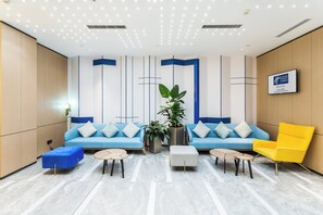 A modern hotel lobby with a blue sofa, a yellow armchair, and a potted plant. - Holiday Inn Express Xi'An Ancient Town West by IHG (Xi'an)