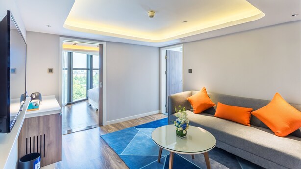 A modern living room with a sofa, coffee table, and a TV. - Holiday Inn Express Xi'An Ancient Town West by IHG (Xi'an)