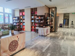 A spacious lobby with a reception desk, a potted plant, and a variety of neatly organized shelves with items. - Holiday Inn Express Xi'An Ancient Town West by IHG (Xi'an)