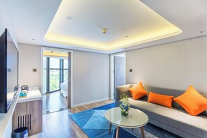 A modern living room with a sofa, coffee table, and a television. - Holiday Inn Express Xi'An Ancient Town West by IHG (Xi'an)