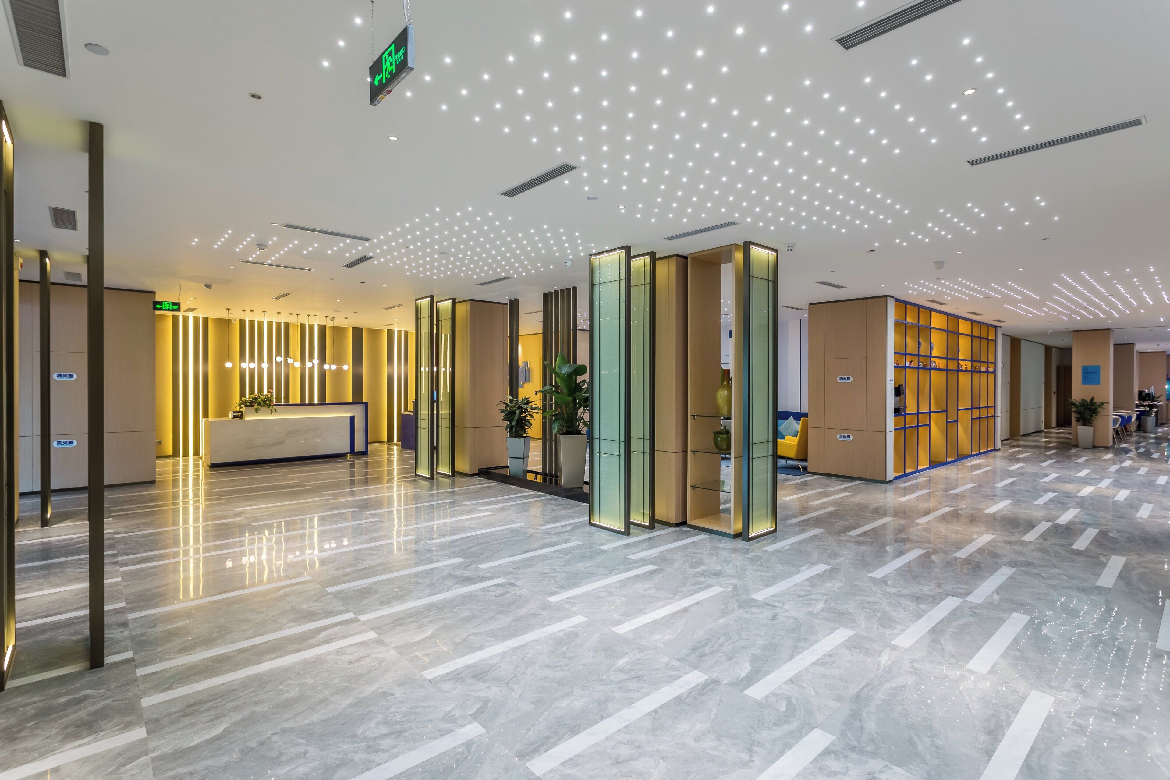 A modern hotel lobby with a reception desk, seating areas, and a patterned floor.