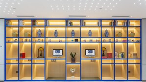 A modern hotel lobby with a large, well-lit blue bookshelf filled with books and decorative items. - Holiday Inn Express Xi'An Ancient Town West by IHG (Xi'an)