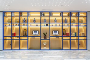 Eine moderne Hotelhalle mit einem großen, gut beleuchteten blauen Bücherregal, gefüllt mit Büchern und Dekoration.