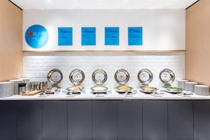 A buffet setup with multiple food stations, each with a round serving tray and labeled with different dishes. - Holiday Inn Express Xi'An Ancient Town West by IHG (Xi'an)