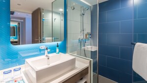 A modern bathroom with a large mirror, a white sink, and a glass-enclosed shower area. - Holiday Inn Express Xi'An Ancient Town West by IHG (Xi'an)