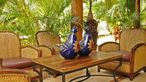 A wicker sofa set with a wooden table in a tropical setting. - Bamboo Manor (Playa del Carmen)