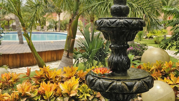 A fountain surrounded by tropical plants and a pool. - Bamboo Manor (Playa del Carmen)