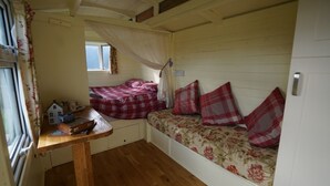 Ein gemütliches Wohnmobil-Interieur mit zwei Betten, einem kleinen Tisch und einem Fenster.
