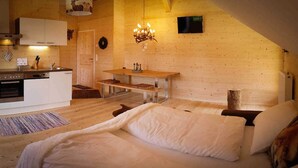 A cozy room with a bed, a wooden table, a kitchen area, and a fireplace. - Steirer Apartment with Small Balcony - Steirer Apartment (Semmering-Kurort)