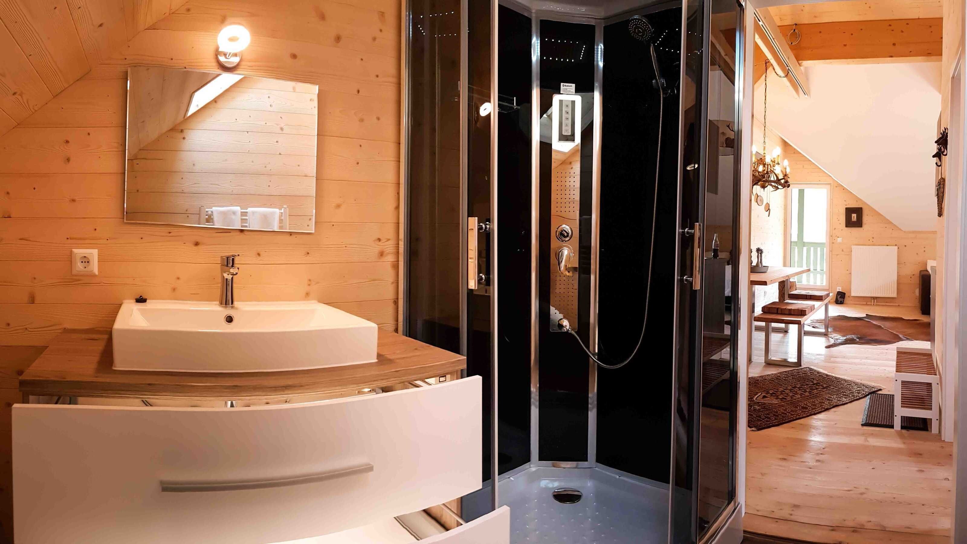 Ein modernes Badezimmer mit einem weißen Waschbecken, einer Duschkabine aus Glas und Holzvertäfelung.