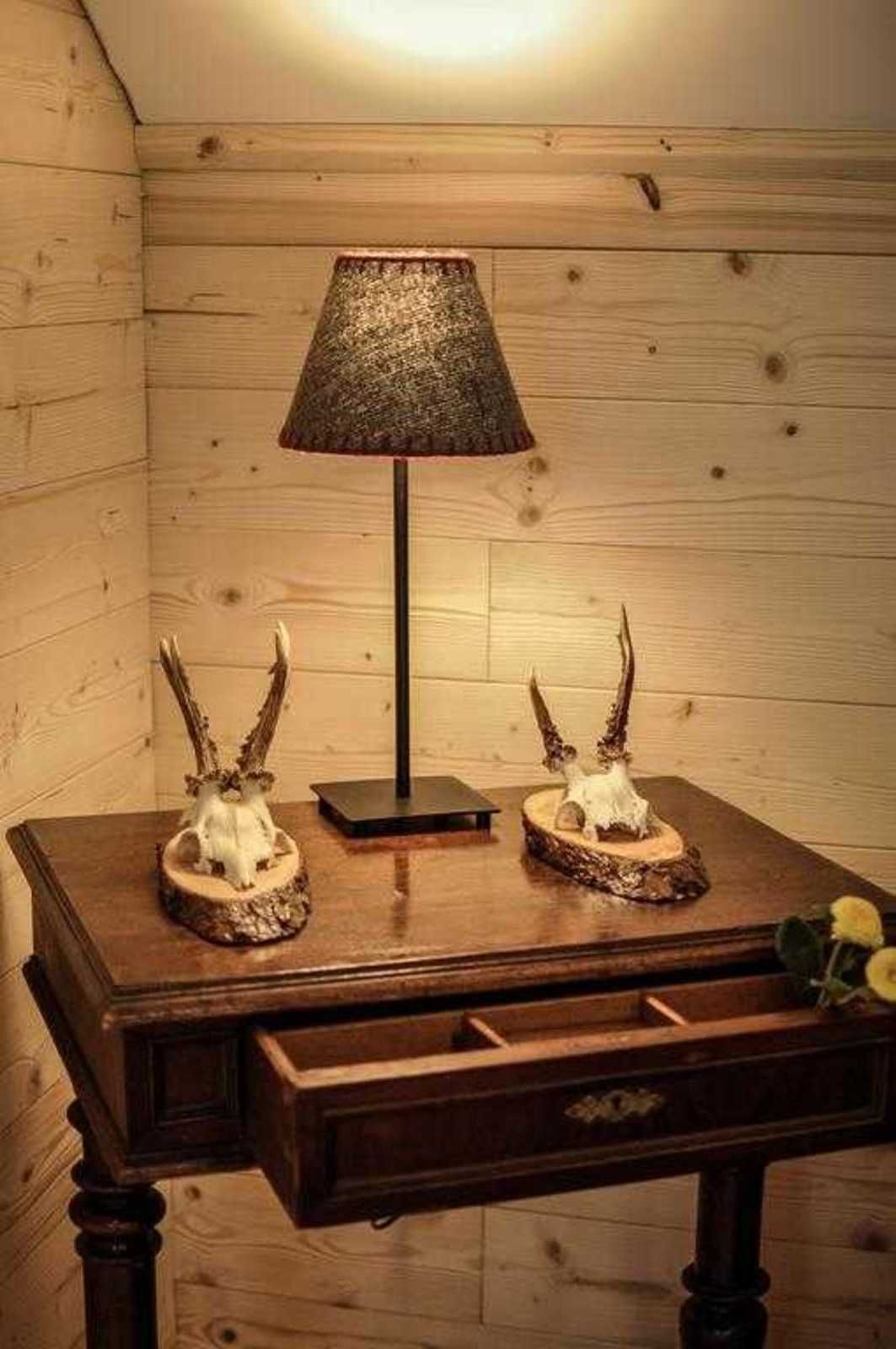 A wooden table with a lamp and two antler-shaped sculptures.