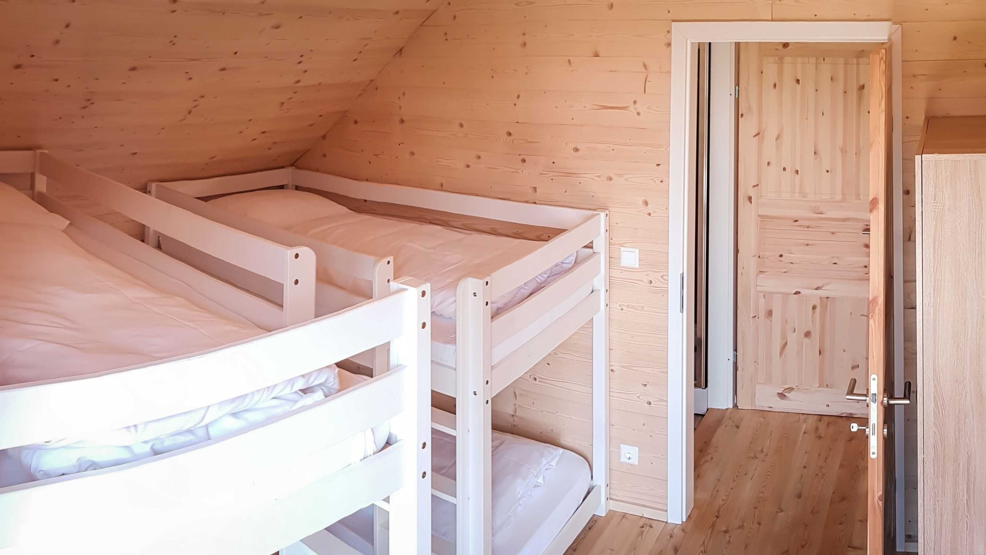 Ein Zimmer mit drei Etagenbetten, Holzwänden und einer Tür.