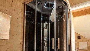 A modern bathroom with a glass-enclosed shower, wooden walls, and a visible towel rack. - Steirer Apartment with Small Balcony - Steirer Apartment (Semmering-Kurort)