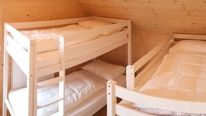 Een slaapkamer met stapelbed, witte beddengoed en houten wanden.