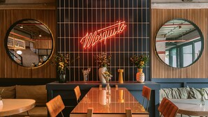 A restaurant interior with a neon sign reading "Mosquito," wooden paneling, round tables, and chairs. - The Somos Beats Hotel  (Medell ín)