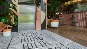 An elevator with a modern design, a reception area with a wooden counter, and a floor with a hexagonal pattern. - The Somos Beats Hotel  (Medellín)