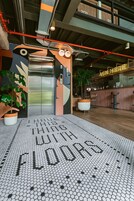 Un ascensor de diseño moderno, un área de recepción con mostrador de madera y un suelo con patrón hexagonal.