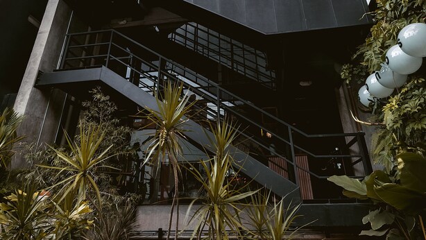 A modern building with multiple levels, balconies with plants, and a staircase leading to the upper floors. - The Somos Beats Hotel  (Medellín)