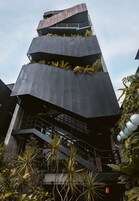 Un edificio moderno con varios niveles, balcones con plantas y una escalera que lleva a los pisos superiores.