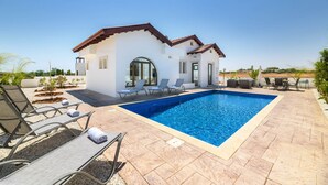 Una casa moderna con piscina, mobiliario exterior y zona de patio.